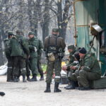 Service members of pro-Russian troops gather in a street in Mariupol